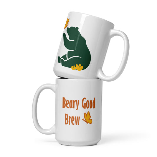 Two 15 oz Beary Good Ceramic mugs stacked one on top of the other. The bottom one shows Petals & Paws logo graphic, a green bear reaching out with a paw toward a butterfly, while sitting in flowers. The top one shows the orange text, "Beary Good Brew" accented by Petals & Paws signature butterfly.