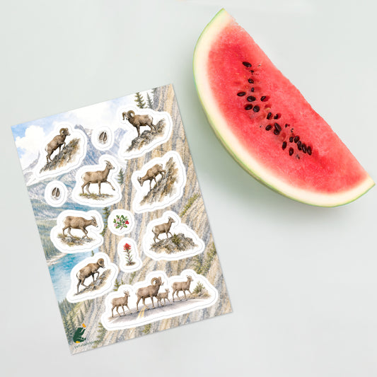 A sheet of kiss-cut stickers featuring Rocky Mountain landscape and bighorn sheep illustrations, placed next to a large slice of watermelon on a light gray background.