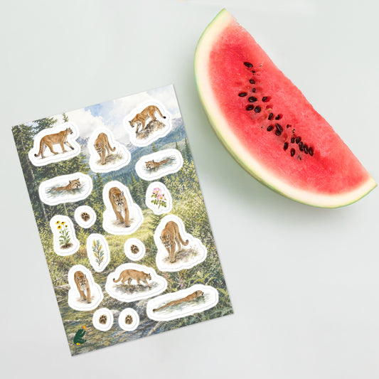 A sheet of kiss-cut stickers featuring traveling cougars (mountain lions) and botanicals, set against Rocky Mountain foothills landscape, and placed next to a large slice of watermelon on a light gray background.