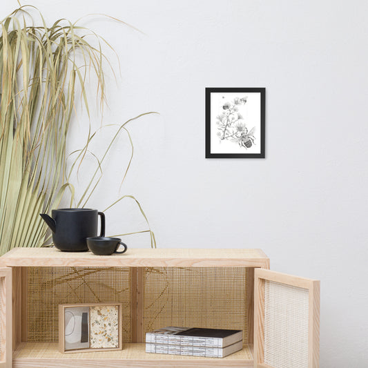 Black framed print of Late Autumn Forage, about bumblebees foraging and pollinating asters, hanging on a wall with surrounding home furnishings. Illustrated by Suzanne Matheson, 2017.