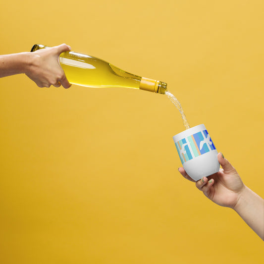 In-action mockup of Petals & Paws Tide Wine Tumbler, featuring seagull design with blue striped pattern. The hand of one person holds a bottle of wine, pouring it into the tumbler held by another person's hand. Background is an orange glow.