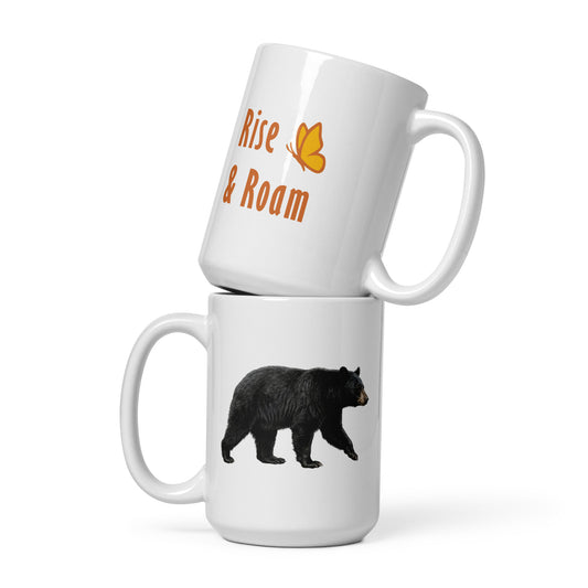 Two 15 oz Rise and Roam Black Bear mugs stacked one on top of the other. The bottom one shows a realistic bear illustration, while the top one shows the orange text, "Rise & Roam" accented by Petals & Paws signature butterfly.