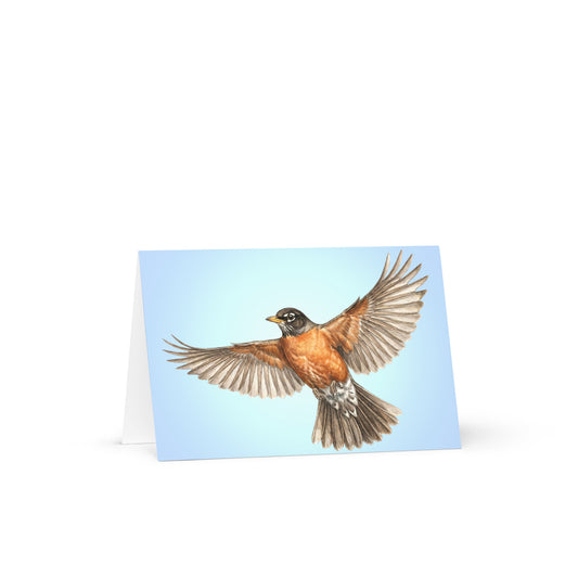 Product mockup of the American Robin Greeting Card, standing open, with a realistic flying robin against a clear blue sky. 