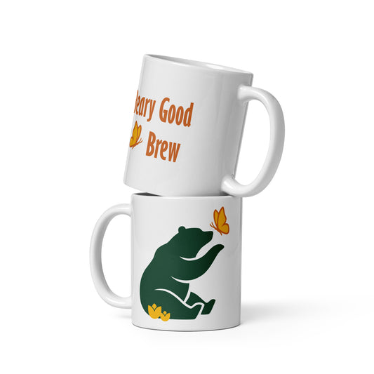 Two 11 oz Beary Good Ceramic mugs stacked one on top of the other. The bottom one shows Petals & Paws logo graphic, a green bear reaching out with a paw toward a butterfly, while sitting in flowers. The top one shows the orange text, "Beary Good Brew" accented by Petals & Paws signature butterfly.