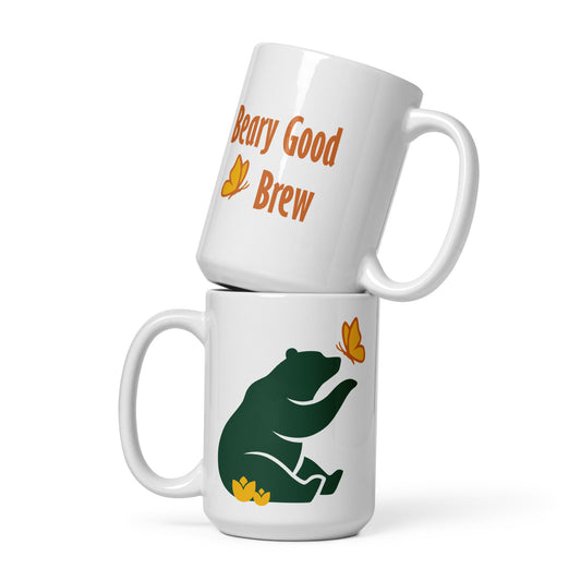 Two 15 oz Beary Good Ceramic mugs stacked one on top of the other. The bottom one shows Petals & Paws logo graphic, a green bear reaching out with a paw toward a butterfly, while sitting in flowers. The top one shows the orange text, "Beary Good Brew" accented by Petals & Paws signature butterfly.