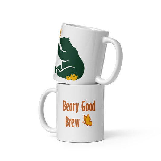 Two 11 oz Beary Good Ceramic mugs stacked one on top of the other. The bottom one shows Petals & Paws logo graphic, a green bear reaching out with a paw toward a butterfly, while sitting in flowers. The top one shows the orange text, "Beary Good Brew" accented by Petals & Paws signature butterfly.