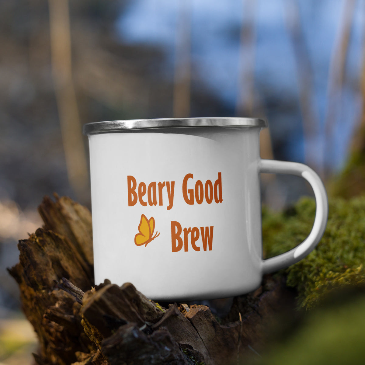 12 oz Beary Good Enamel Mug for left-hand orientation sits on a moss-covered stump outside.  The orange "Beary Good Brew" text and butterfly accent are revealed.