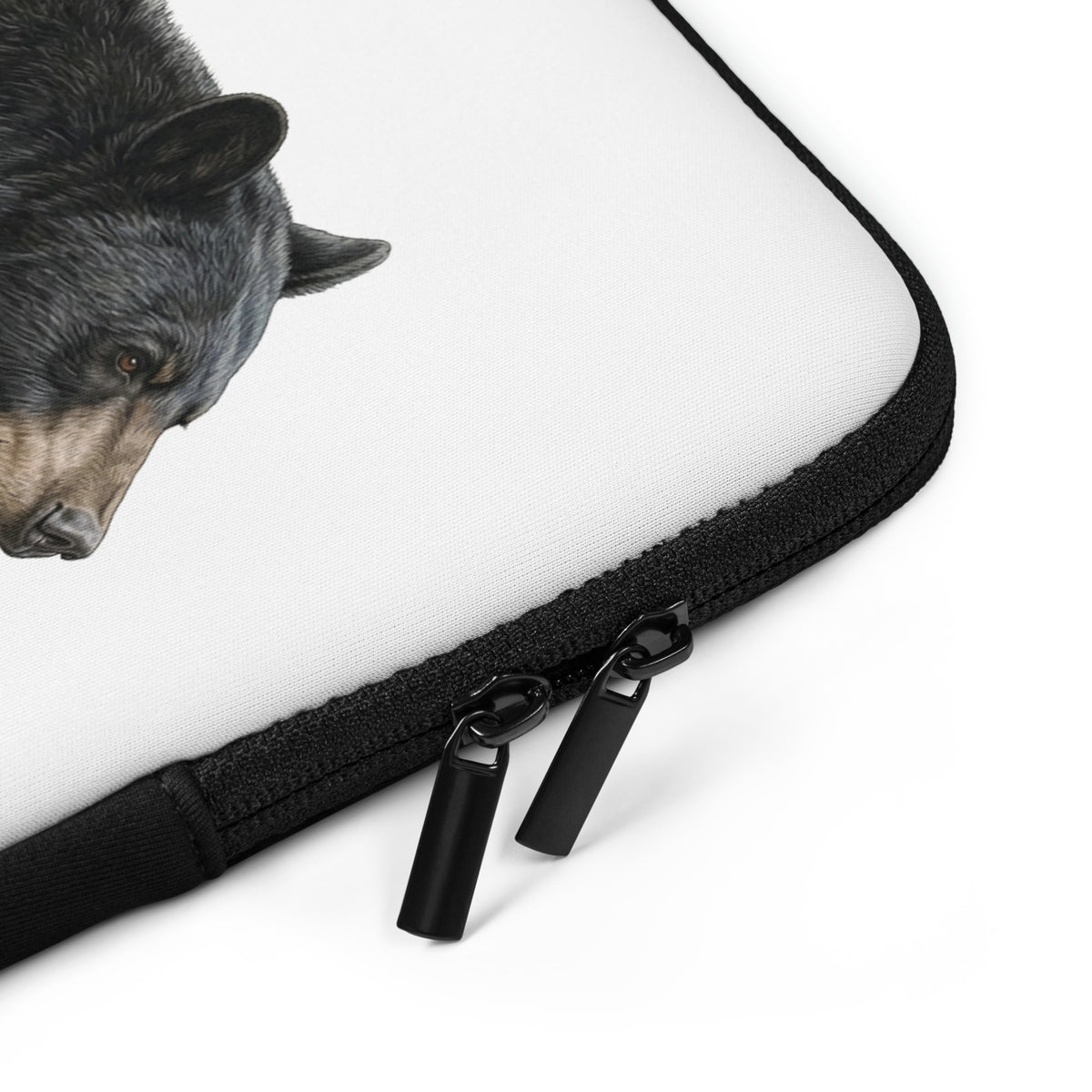 Close-up of the black zipper and trim surrounding the white surface of 13 inch Black Bear Laptop Sleeve. The bear illustration is partly visible.
