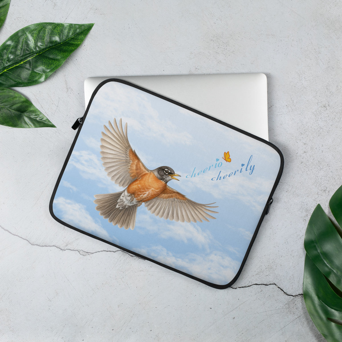 In-action product mockup of the Cheerily Robin Laptop Sleeve, with a flying robin, singing, "cheerio cheerily" against a fair blue sky and fluffy cloud background.  A laptop is inside and partially showing.