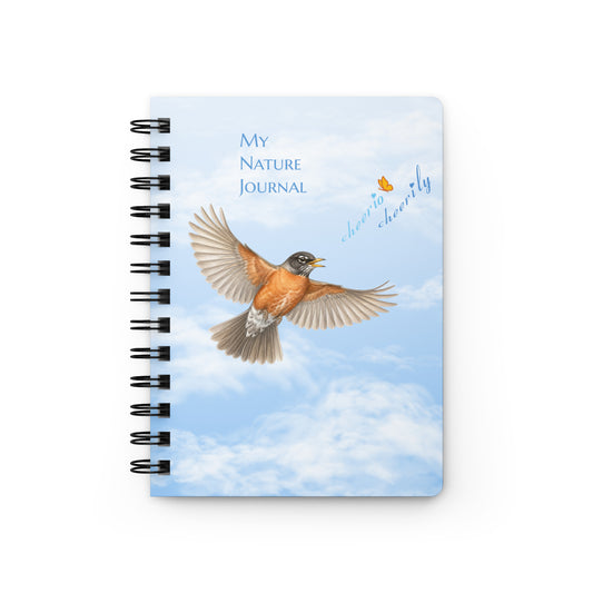 Product mockup of the spiral-bound Cheerily Robin Nature Journal, with a flying robin, singing, "cheerio cheerily" against a fair blue sky and fluffy cloud background. The Petals & Paws orange and yellow butterfly accents the songster's text.  Other text says, "My Nature Journal."