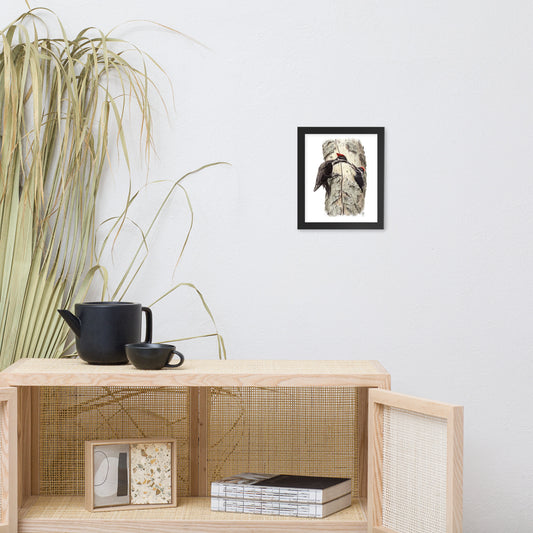 Black framed print of Coaxing Courage, about Pileated Woodpecker parenting, hanging on a wall with surrounding livingroom furnishings.  Illustrated by Suzanne Matheson, 2017.
