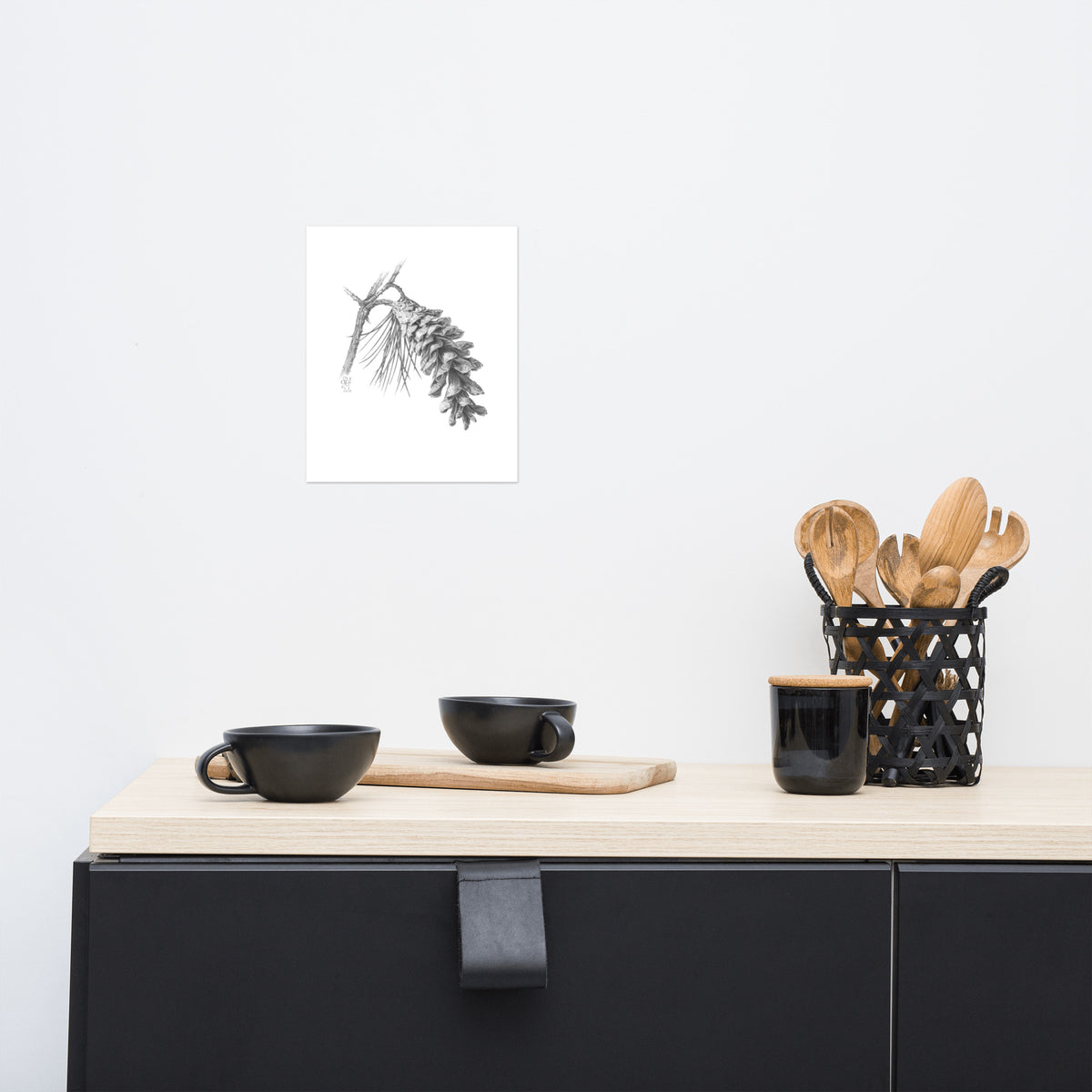 Museum-quality print of Pinus strobus - Eastern White Pine, graphite depiction of an Eastern white pinecone on a winter-bare branch, hanging on a wall with surrounding home furnishings.  Illustrated by Suzanne Matheson, 2017.