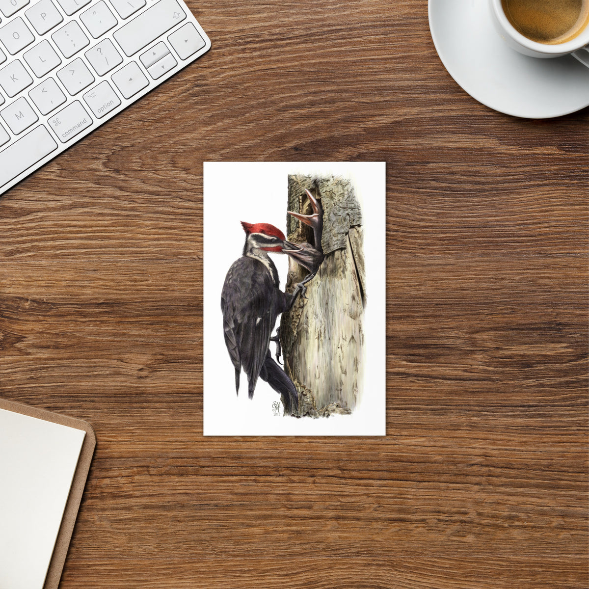 Product mockup of The Hungry Hour Greeting Card, shown on an office desk surrounded by a keyboard, teacup and clipboard.