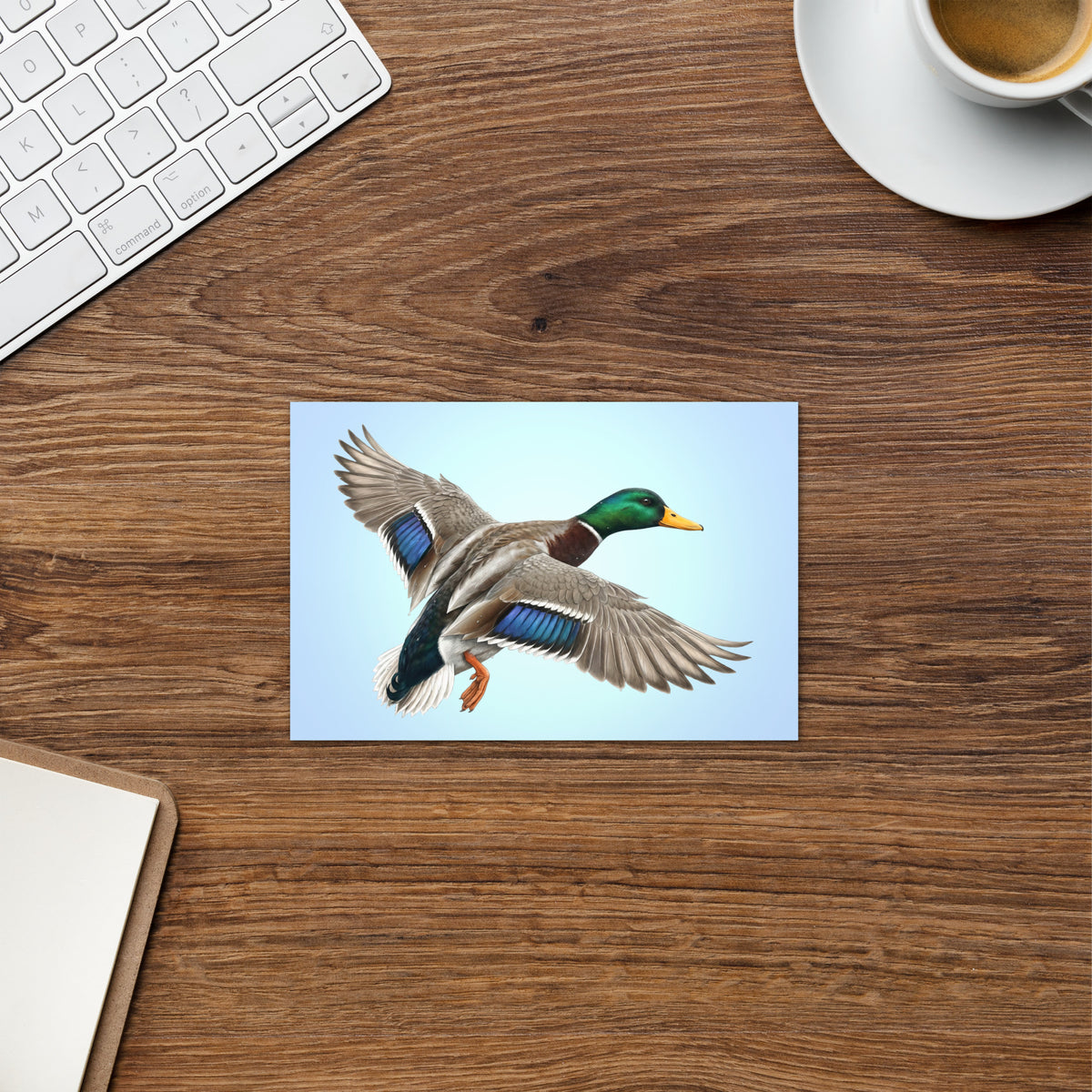 Product mockup of the Mallard Duck Greeting Card, shown on a desk with a coffee cup, keyboard and clipboard.