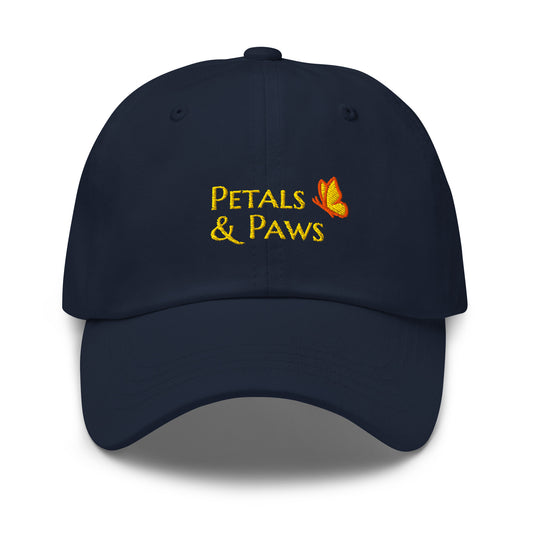 Product mockup of navy Petals & Paws Classic Dad Hat.  This ball cap front features "Petals & Paws" in the brand's signature font, Marcellus SC, in gold embroidery accented with the brands butterfly.