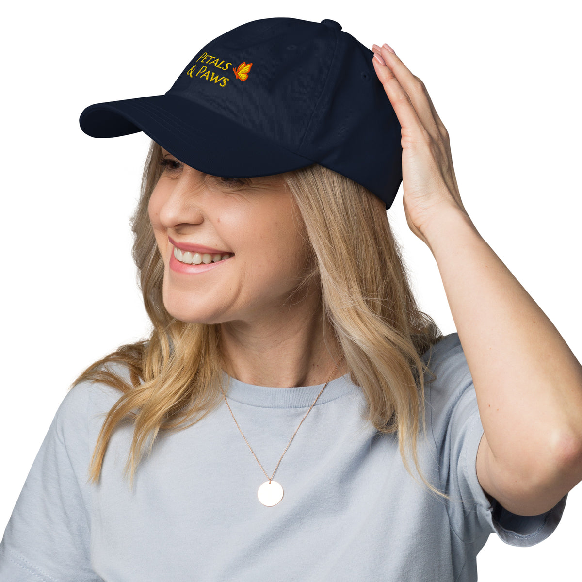 A woman with blonde hair wearing the navy Petals & Paws Classic Dad Hat, three-quarter view.