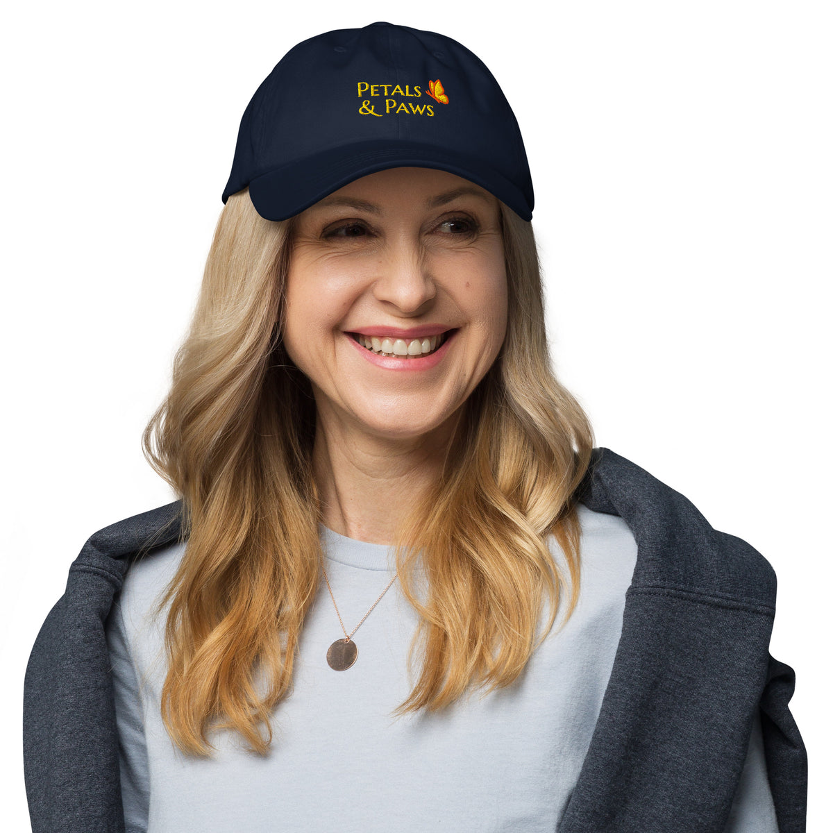 A woman with blonde hair wearing the navy Petals & Paws Classic Dad Hat. Front view.