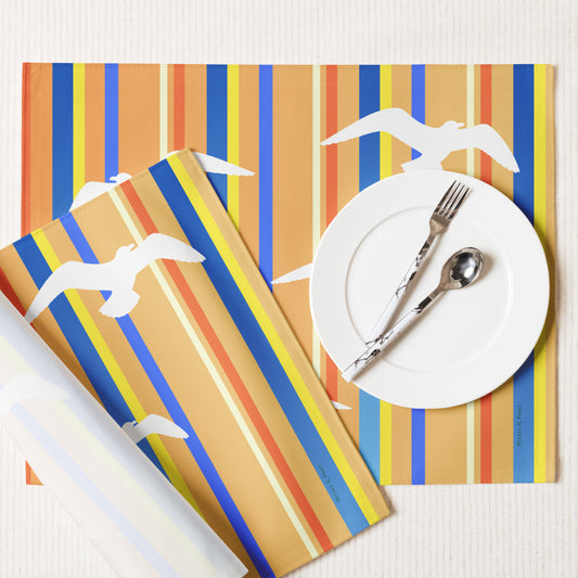 Product mockup of a Petals & Paws Drift Placemat, featuring seagull design with orange striped pattern. This image shows the white back and hemmed edges.