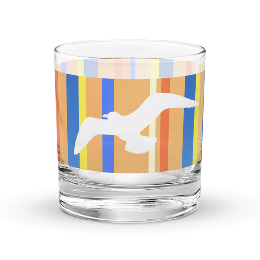 Product mockup of 10.5 oz Petals & Paws Drift Rocks Glass, featuring seagull design with orange striped pattern.
