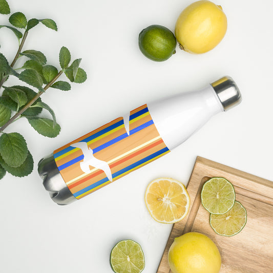 A 17 oz Petals & Paws Drift Water Bottle laying on its side amidst citrus fruit and an herb plant. This bottle features seagull design with orange striped pattern.