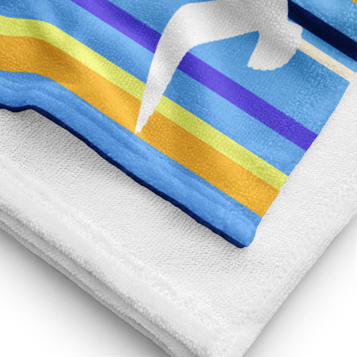 A close-up view of folded 30 x 60" Petals & Paws Shoreline Beach Towel, revealing the print of seagull design with blue striped pattern on terry fabric and the white back surface.