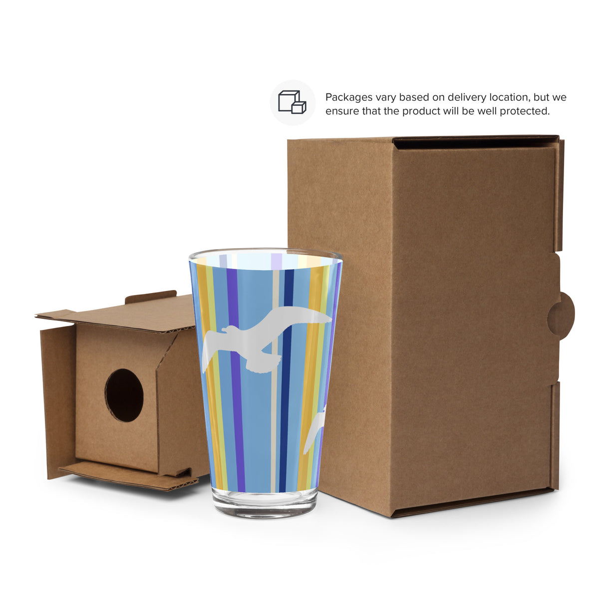 Cardboard packaging surrounds a Petals & Paws Shoreline Pint Glass. Text says, "Packages vary based on delivery location, but we ensure that the product will be well protected."