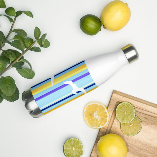 A 17 oz Petals & Paws Shoreline Water Bottle laying on its side amidst citrus fruit and an herb plant. This bottle features seagull design with blue striped pattern.