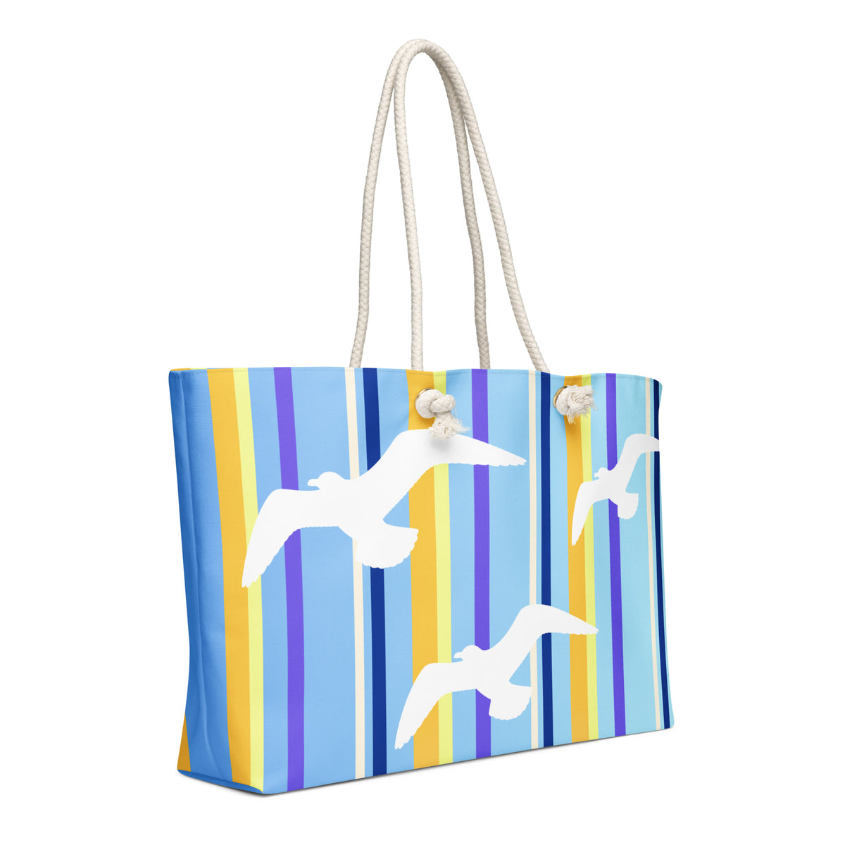 A diagonal view of Petals & Paws Shoreline Weekender Bag showing the pattern as it wraps around the ends of the bag. This all-over print bag features seagull design with blue striped pattern and cream-colored cotton rope handles.