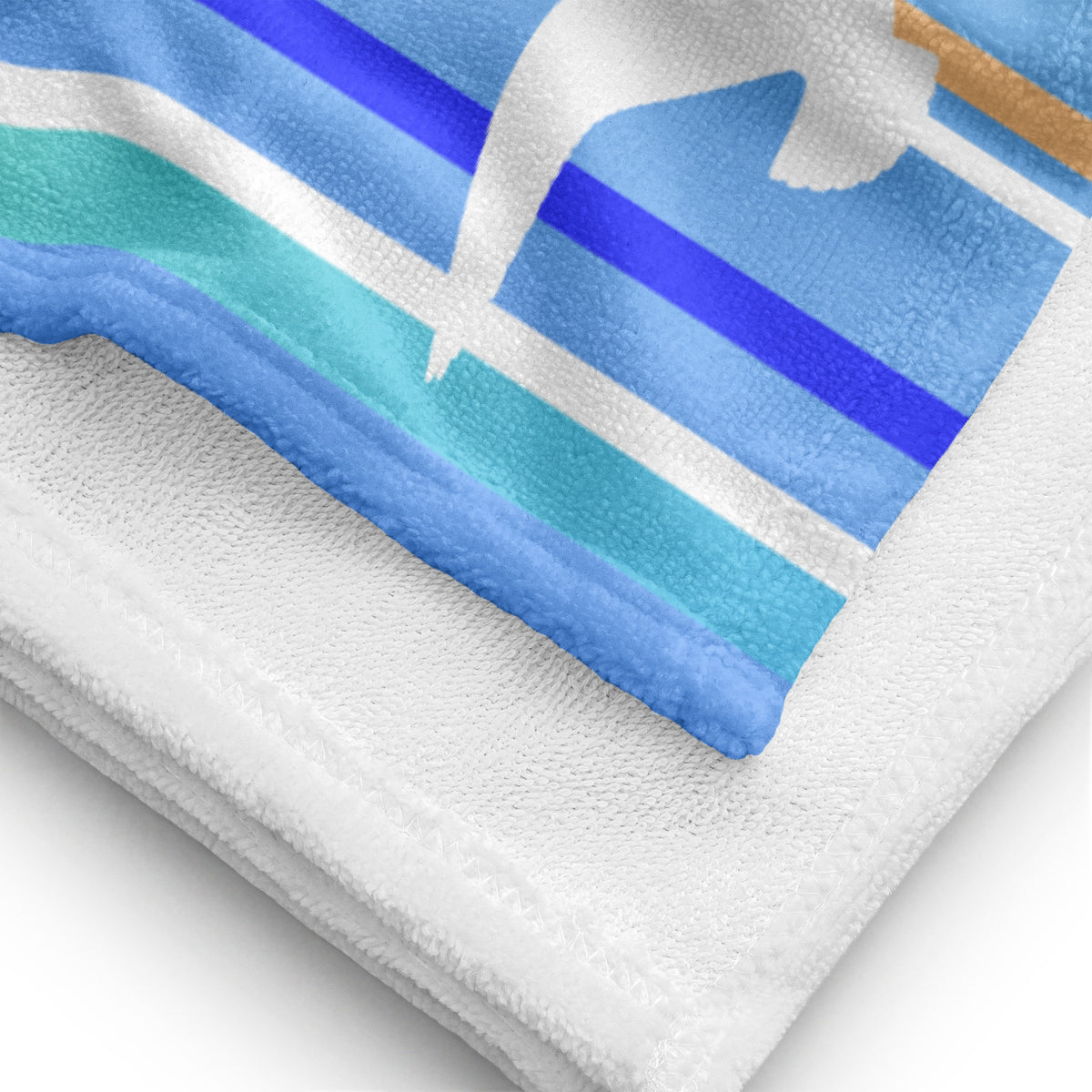 A close-up view of folded 30 x 60" Petals & Paws Tide Beach Towel, revealing the print of seagull design with blue striped pattern on terry fabric and the white back surface.