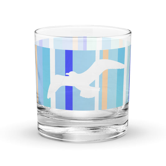 Product mockup of 10.5 oz Petals & Paws Tide Rocks Glass, featuring seagull design with blue striped pattern.