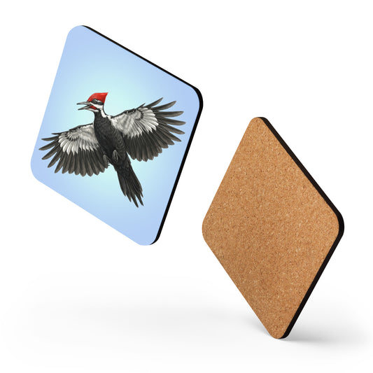 Two square Pileated Woodpecker coasters appear to be dancing against a white background, one showing the woodpecker is flying against a clear blue sky on the front, while the other shows the cork on the back.