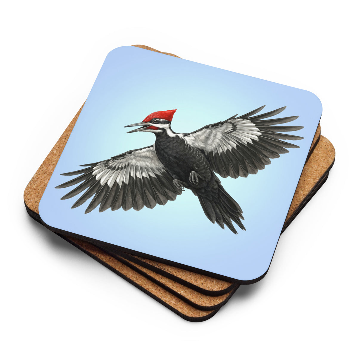 Product mockup of a stack of four Pileated Woodpecker Coasters.  The top one reveals the woodpecker is flying against a clear blue sky, while the ones underneath are flipped upside down to reveal their cork-backs.