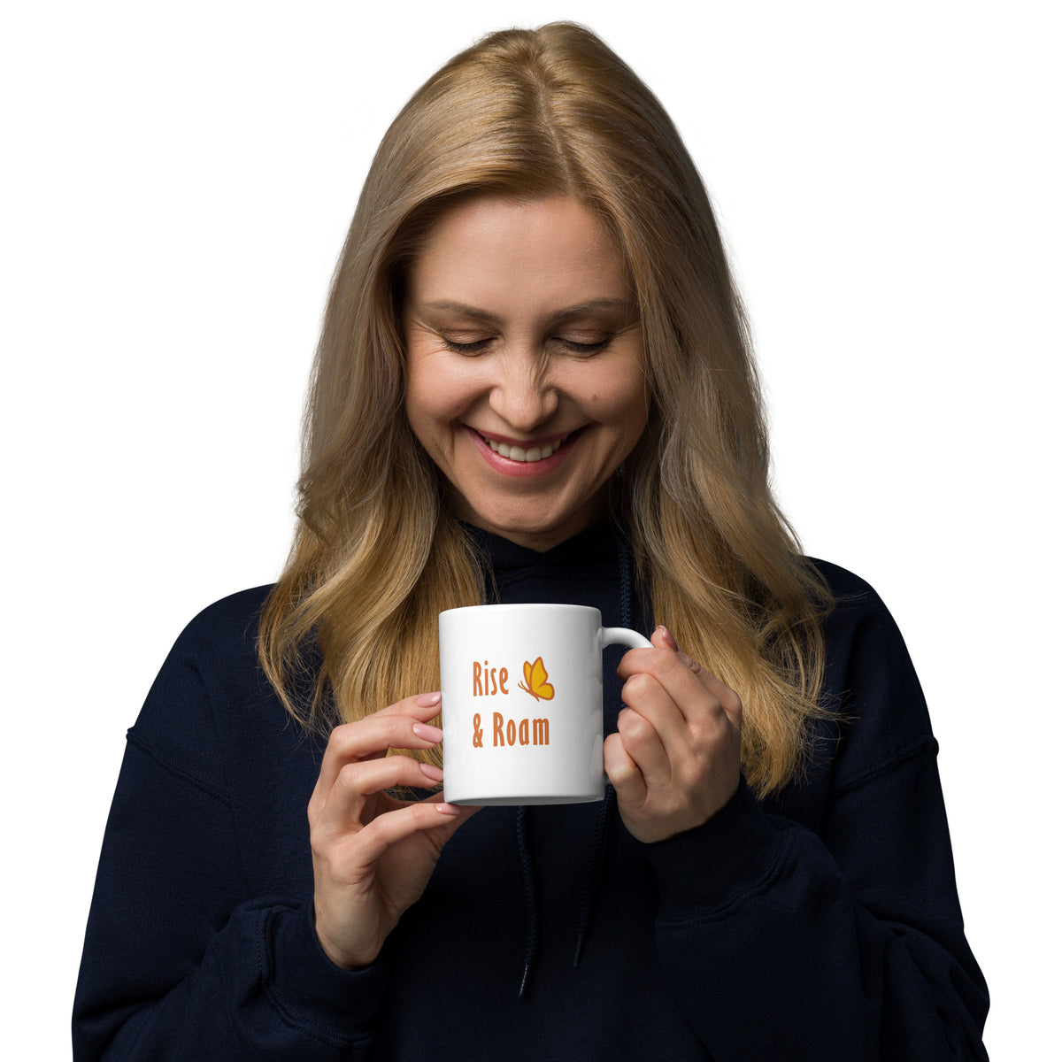 A woman holding and looking into her 11 oz Rise and Roam Black Bear Mug. She holds the handle in her left hand so that the orange text, "rise & Roam" with Petals & Paws butterfly accent is facing out.