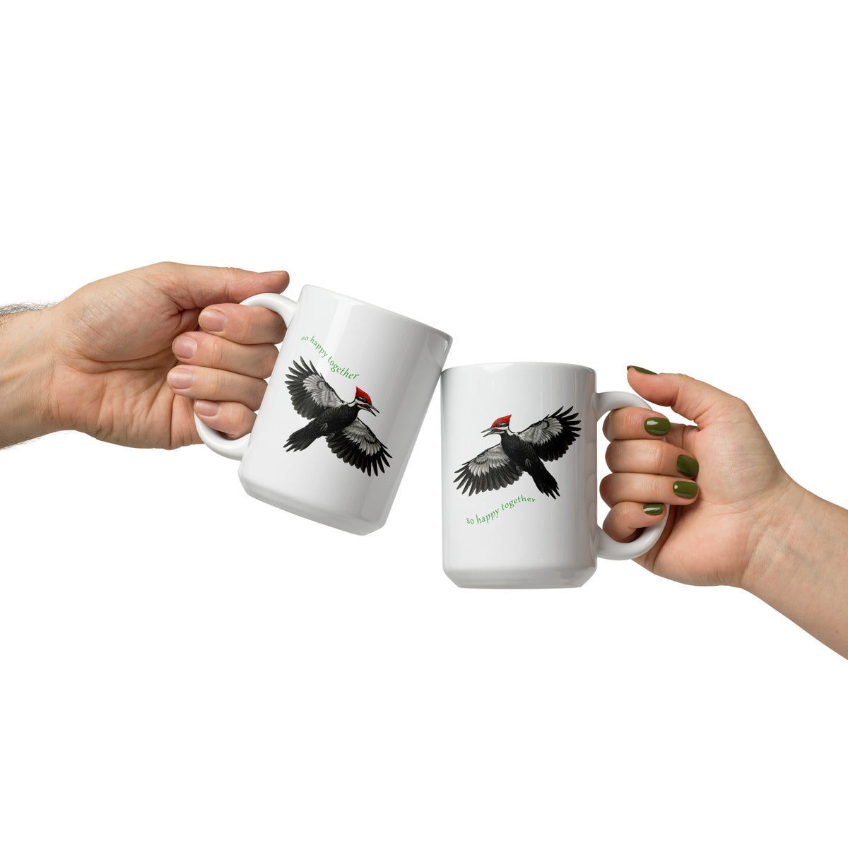 Two hands holding white So Happy Together 15 oz mugs in a motion that says, "Cheers!" The mugs feature realistic Pileated Woodpecker illustrations flying against a white background.