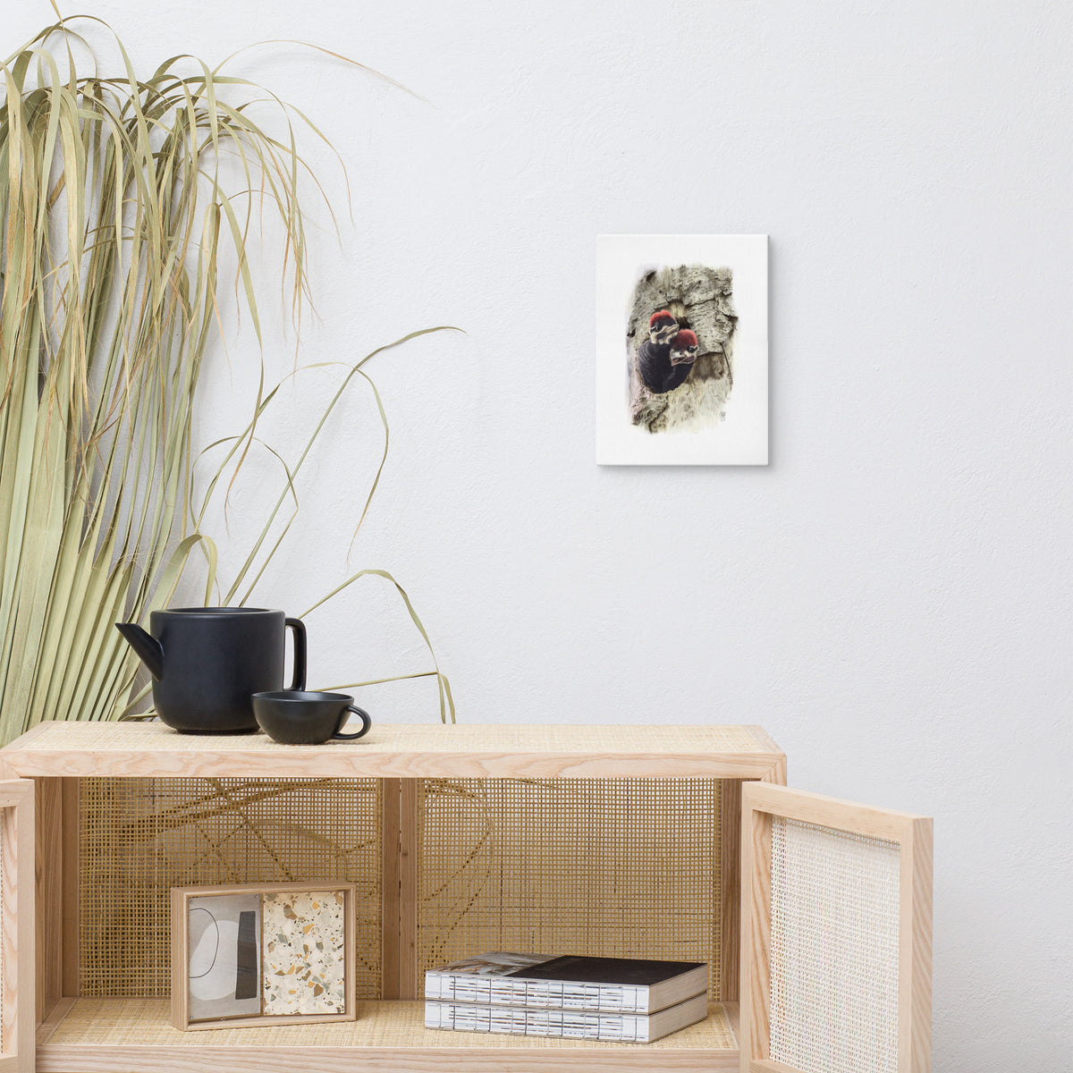 Gallery-wrapped canvas of Two at the Door, about Pileated Woodpeckers, hanging on a wall with surrounding home furnishings.  Illustrated by Suzanne Matheson, 2017.